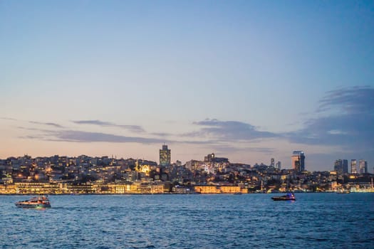 Istanbul at sunset, Turkey. Tourist boat sails on Golden Horn in summer. Beautiful sunny view of Istanbul waterfront with old mosque. Concept of travel, tourism and vacation in Istanbul and Turkey. Turkiye.