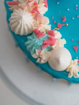studio shot of chocolate frosted blue dripped icing white cup cake, unicorn , meringue and sprinkles on top