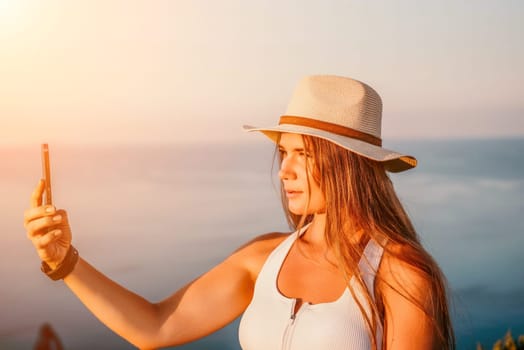 Woman travel sea. Happy tourist in hat enjoy taking picture outdoors for memories. Woman traveler posing on the beach at sea surrounded by volcanic mountains, sharing travel adventure journey