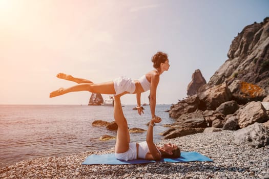 Woman sea yoga. Back view of free calm happy satisfied woman with long hair standing on top rock with yoga position against of sky by the sea. Healthy lifestyle outdoors in nature, fitness concept.