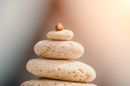 Pyramid stones on the seashore with warm sunset on the sea background. Happy holidays. Pebble beach, calm sea, travel destination. Concept of happy vacation on the sea, meditation, spa, calmness.