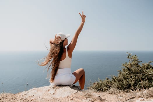 Woman travel sea. Young Happy woman in a long red dress posing on a beach near the sea on background of volcanic rocks, like in Iceland, sharing travel adventure journey