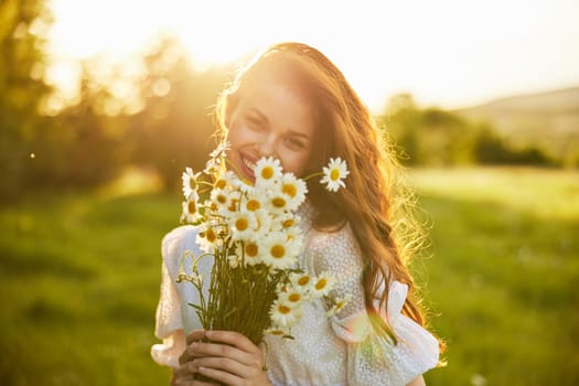 close portrait of a laughing woman looking at the camera in nature with a bouquet of daisies. High quality photo