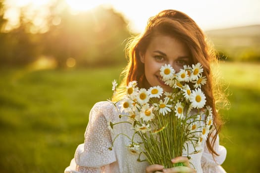 close portrait of a laughing woman looking at the camera in nature with a bouquet of daisies. High quality photo
