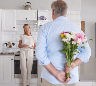 Elderly, couple and flowers in kitchen for surprise, love and romance in their house. Woman, man and retirement together with bouquet to celebrate marriage, birthday or anniversary in their home.