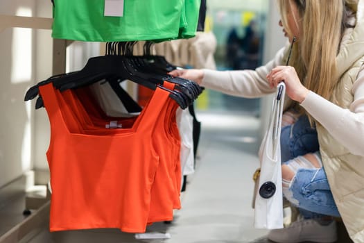 Happy young woman buying new clothes in store. Sale shopping fashion and people concept.