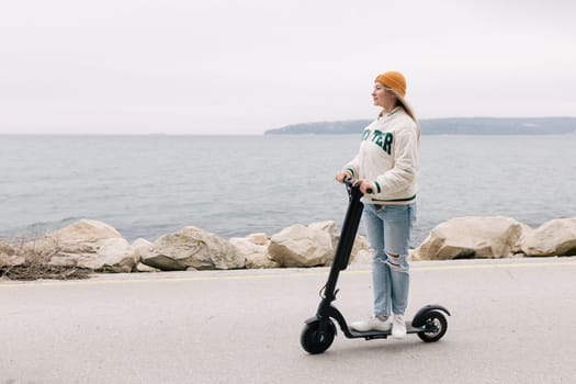 Milan, Italy - February 21, 2018: Attractive girl riding an electric scooter along the promenade in Europe.