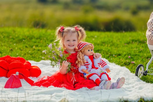 girl sitting with her doll on a blanket