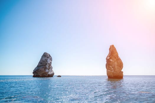 Two rocks stick out of the water in the middle of the turquoise sea. Scenic ocean views. High quality photo. Like in Iceland.