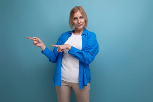 portrait of a blond attractive middle-aged woman in a casual stylish shirt on a blue background with copy space.