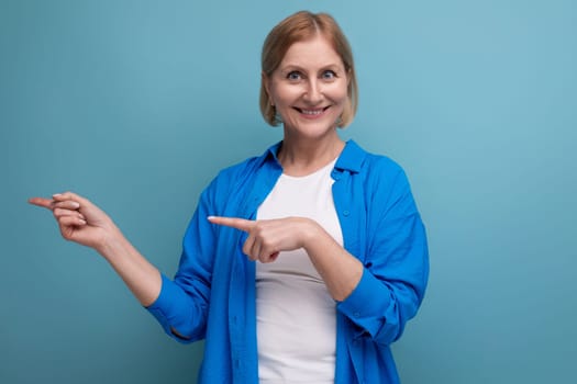 smiling genius blond middle aged woman on blue background with copyspace.