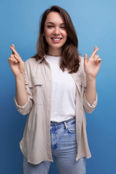 pretty european young brunette woman in shirt and jeans on blue background.