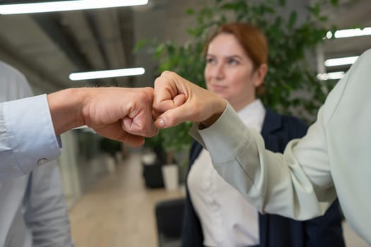 Caucasian man bumping his fists with colleagues as a sign of success