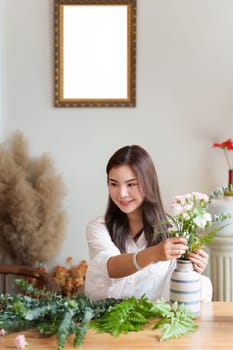 Startup, small business, flower shop. Young pretty florist putting a flower on a vase.