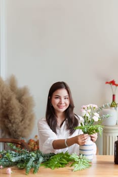 Startup, small business, flower shop. Young pretty florist putting a flower on a vase.