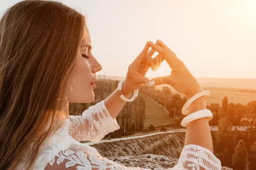 Romantic beautiful bride in white dress posing with sea and mountains in background. Stylish bride standing back on beautiful landscape of sea and mountains on sunset