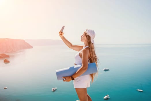 Young woman with black hair, fitness instructor in pink sports leggings and tops, doing pilates on yoga mat with magic pilates ring by the sea on the beach. Female fitness daily yoga concept