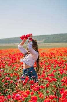 Happy woman in a poppy field in a white shirt and denim skirt with a wreath of poppies on her head posing and enjoying the poppy field