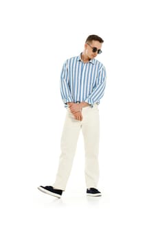 Young fashionable guy in trendy sunglasses, blue striped shirt and trousers isolated on white background. full length.