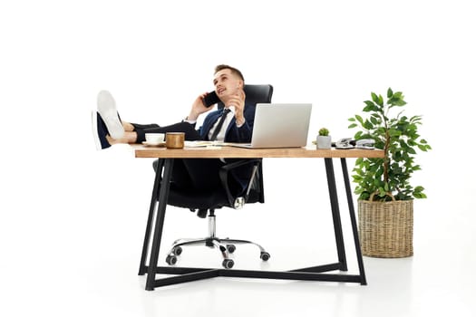 Successful happy businessman working with laptop and having phone conversation with client