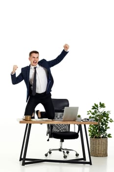Satisfied young businessman gesturing emotionally and celebrating victory in the office