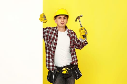 professional builder in work clothes in helmet holding hammer. copy space for text