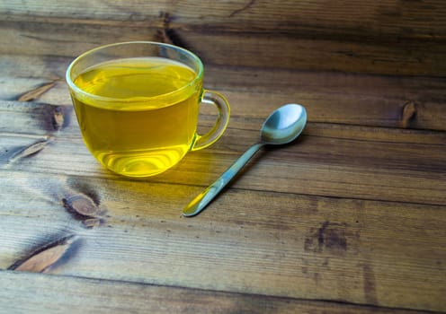 Green tea and spoon. Green tea and a spoon on a wooden table.