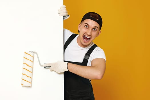 surprised young man in working clothes painting white walls in the room. copy space for text