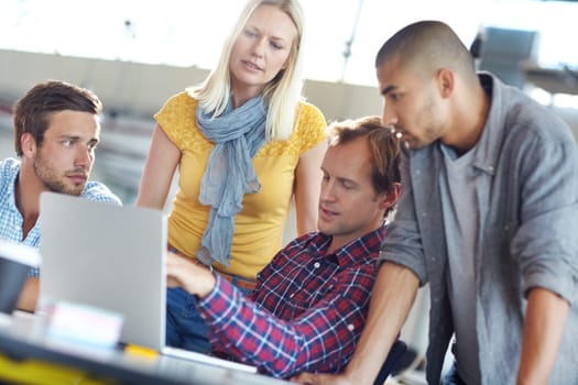 The key to success is hard work and determination. a diverse group of designers working on a laptop in an office