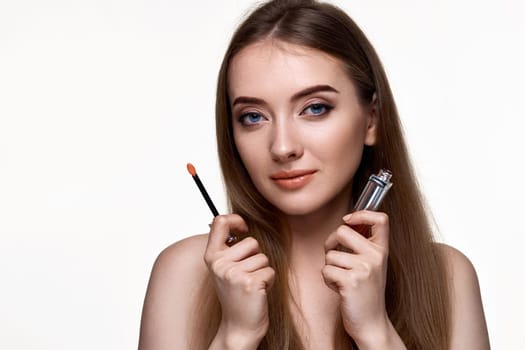 pretty young woman testing nude lip gloss isolated on white background