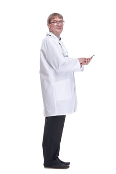 side view. smiling doctor with a smartphone looking at you .isolated on a white background.