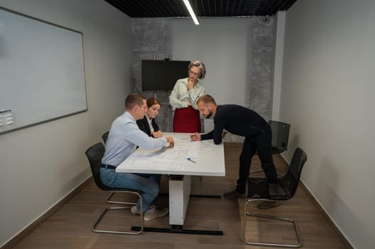 The female boss evaluates the work of subordinates. Designers engineers at a meeting