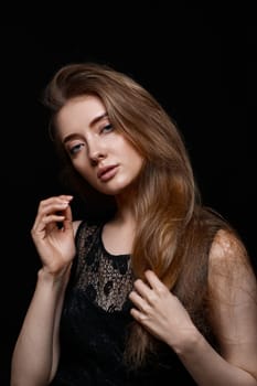 gorgeous brunette woman with long hair in black dress on black background