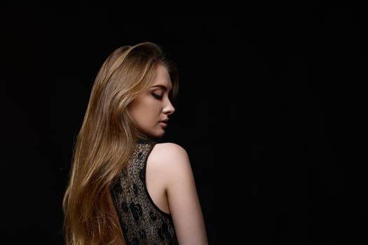 gorgeous brunette woman with long hair in black dress on black background. copy space
