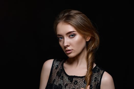 gorgeous brunette woman with long hair in black dress on black background. copy space