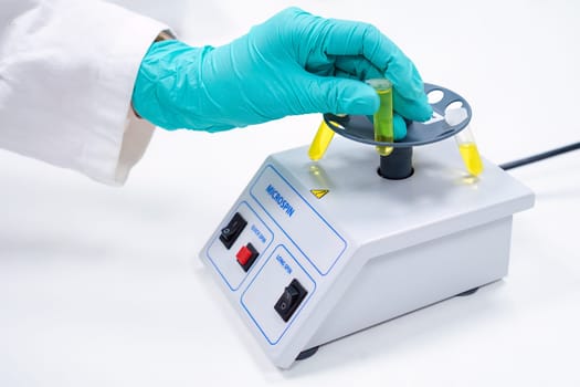 Scientist puts test tube to micro spin for phase separation for microbiological analysis