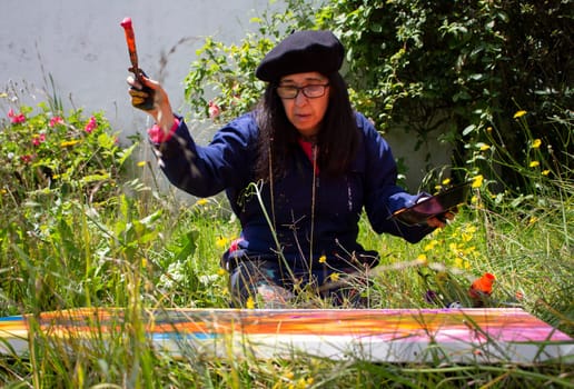 retired woman painting an abstract picture at the creative peak in a garden surrounded by plants. High quality photo