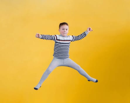 Happy boy jumping on a yellow background