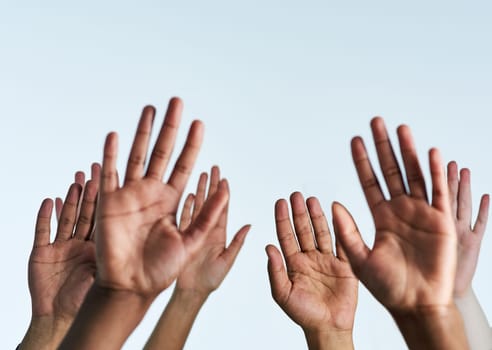 Shot of a group of hands reaching up against a white background.