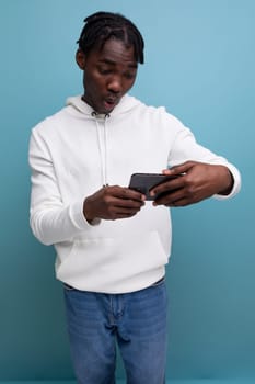 young american guy in white sweatshirt watching video on mobile phone.
