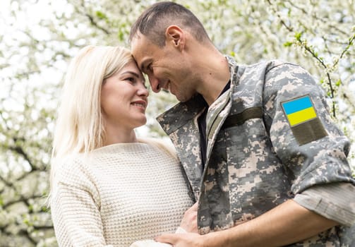 Soldier in military uniform reunited with his family and Ukrainian flag.