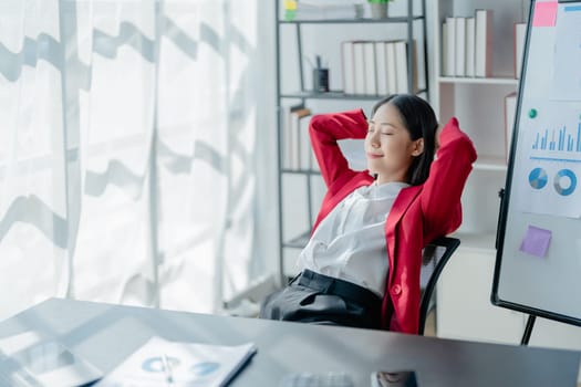 Rear view young businesswoman leaning back in comfortable chair, sitting in modern office, successful woman employee, planning future, visualizing, pondering project strategy