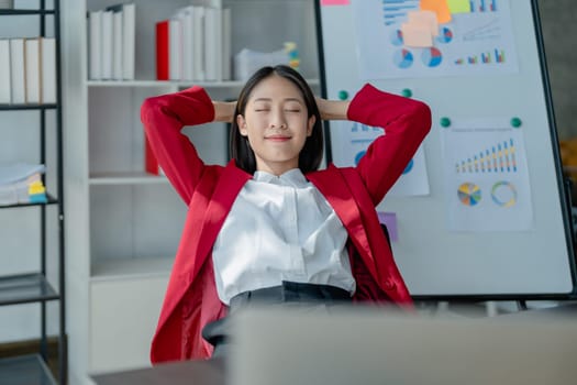 Rear view young businesswoman leaning back in comfortable chair, sitting in modern office, successful woman employee, planning future, visualizing, pondering project strategy
