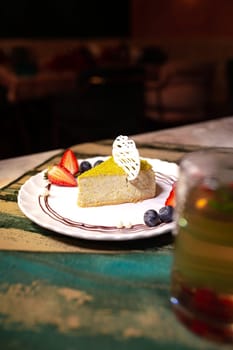 pistachio cheesecake with berries on a plate in a restaurant.