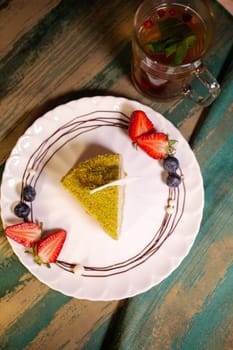 top view pistachio cheesecake with berries on a plate in a restaurant.