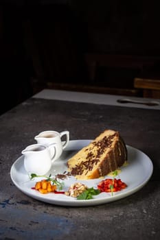 sponge dessert with chocolate chips and fruit on a white plate.