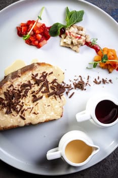 sponge dessert with chocolate chips and fruit on a white plate.