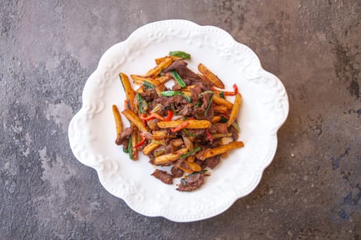 top view fried french fries and meat with pepper and spices on a white plate.