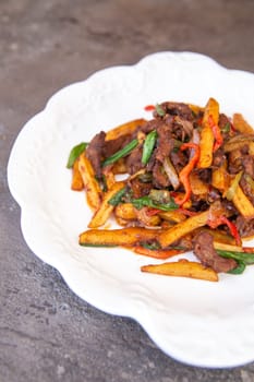 fried french fries and meat with pepper and spices on a white plate.