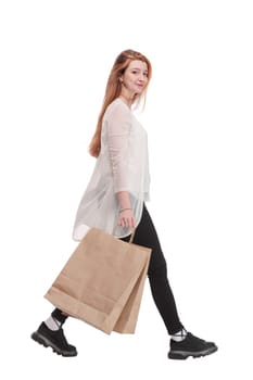 Side view of going beautiful girl with shopping bags. Isolated over white background